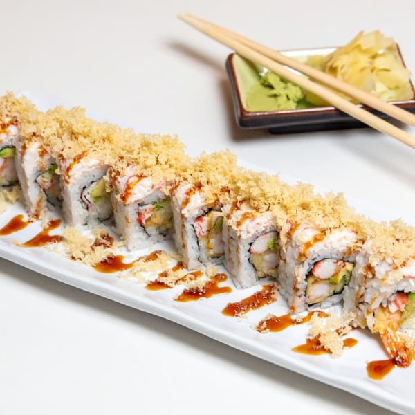 A long plate of Kawaii Sushi's crispy tempura sushi rolls with sauce, wasabi, ginger, and chopsticks.