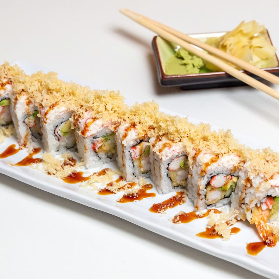 A long plate of Kawaii Sushi's crispy tempura sushi rolls with sauce, wasabi, ginger, and chopsticks.