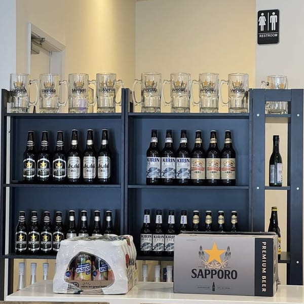 A display shelf with various Japanese beers like Sapporo, Asahi, and Kirin, along with branded mugs.
