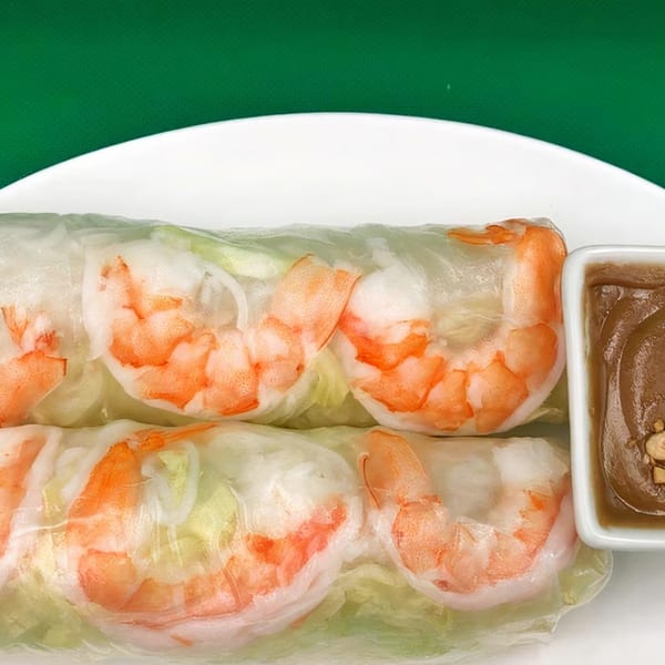 Two fresh shrimp spring rolls with lettuce and rice noodles, served with a side of peanut sauce.