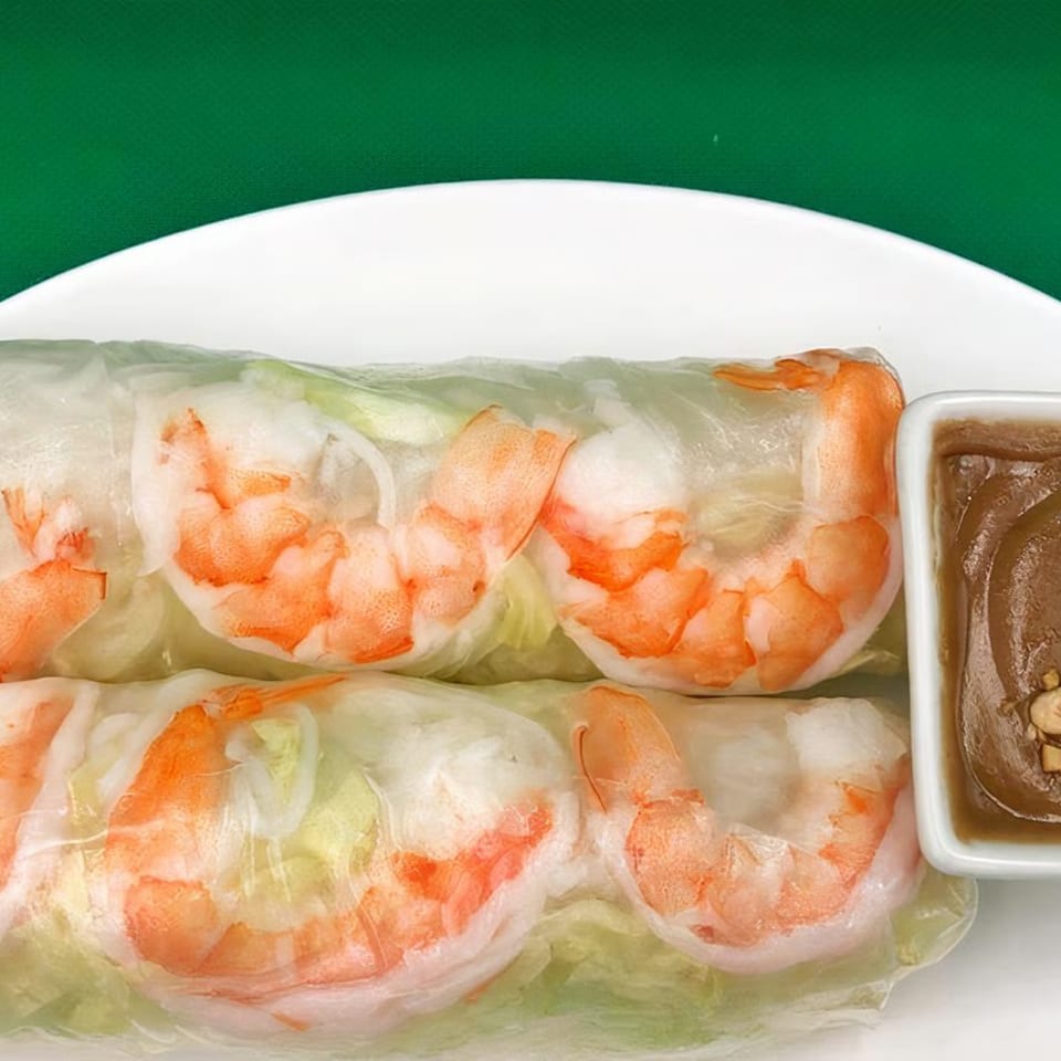 Two fresh shrimp spring rolls with lettuce and rice noodles, served with a side of peanut sauce.